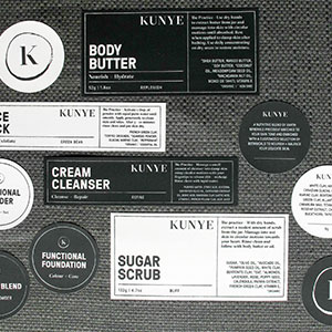 Black and white cosmetic labels in different shapes on a gray texture.