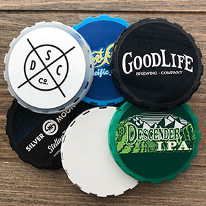 Various keg caps labels on a wooden surface.