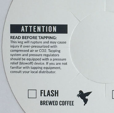 A white keg label that reads "Attention, read before tapping".