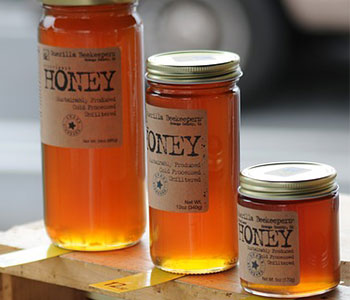A small, medium, and big glass jar of honey with a metal lid.