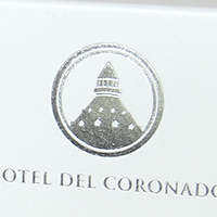 A silver foil with a label that represents a lighthouse and reads "Hotel del Coronado".