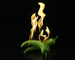 Two chilli peppers burning on a black background.