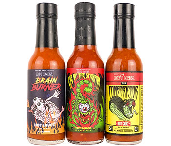 Three glass bottles of hot sauces with cartooned labels.
