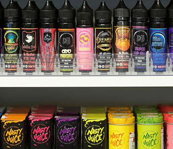 A shelf that displays multiple vape bottles with different aromas.