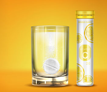A transparent glass of water with a vitamin in it and a golden container of vitamins.