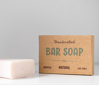一個紙板包裝，上面寫著“Handcrafted Bar Soap Natural”和旁邊的肥皂。