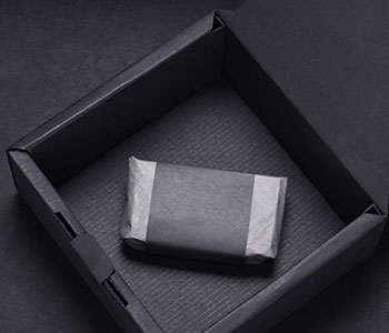 Opened black box and inside a soap wrapped in a black and white paper.